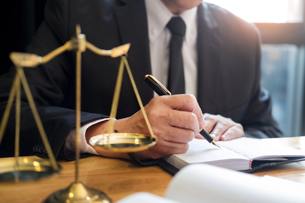 Lawyer writing in notebook with scales of justice on desk, representing personal injury law in Cranford NJ.