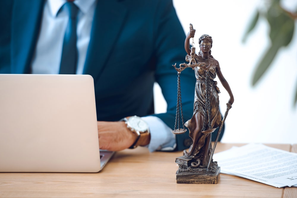 Lady Justice statue beside attorney working on laptop, representing personal injury law in Woodbridge NJ.